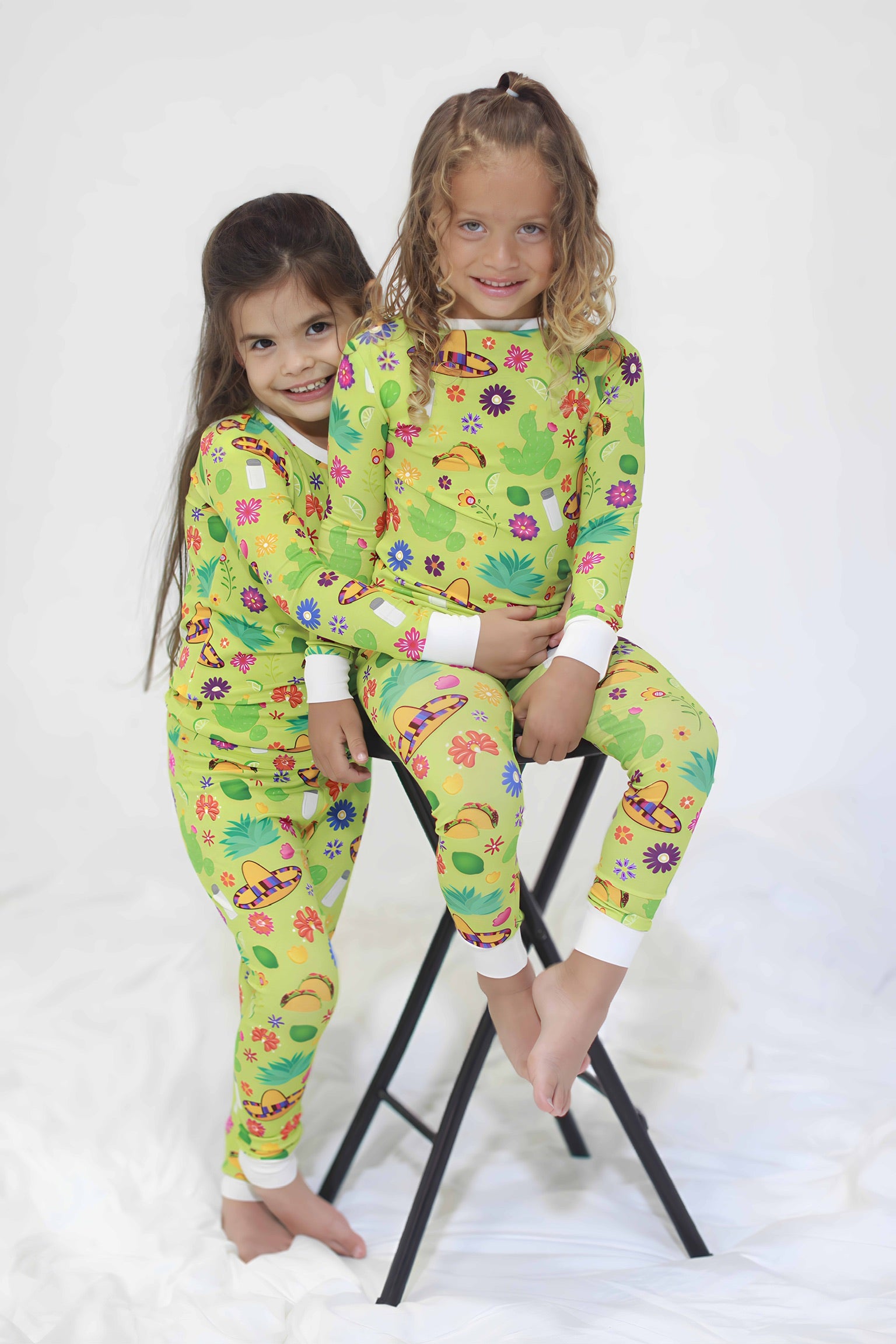 Two children wearing colorful green pajamas with tacos and flowers