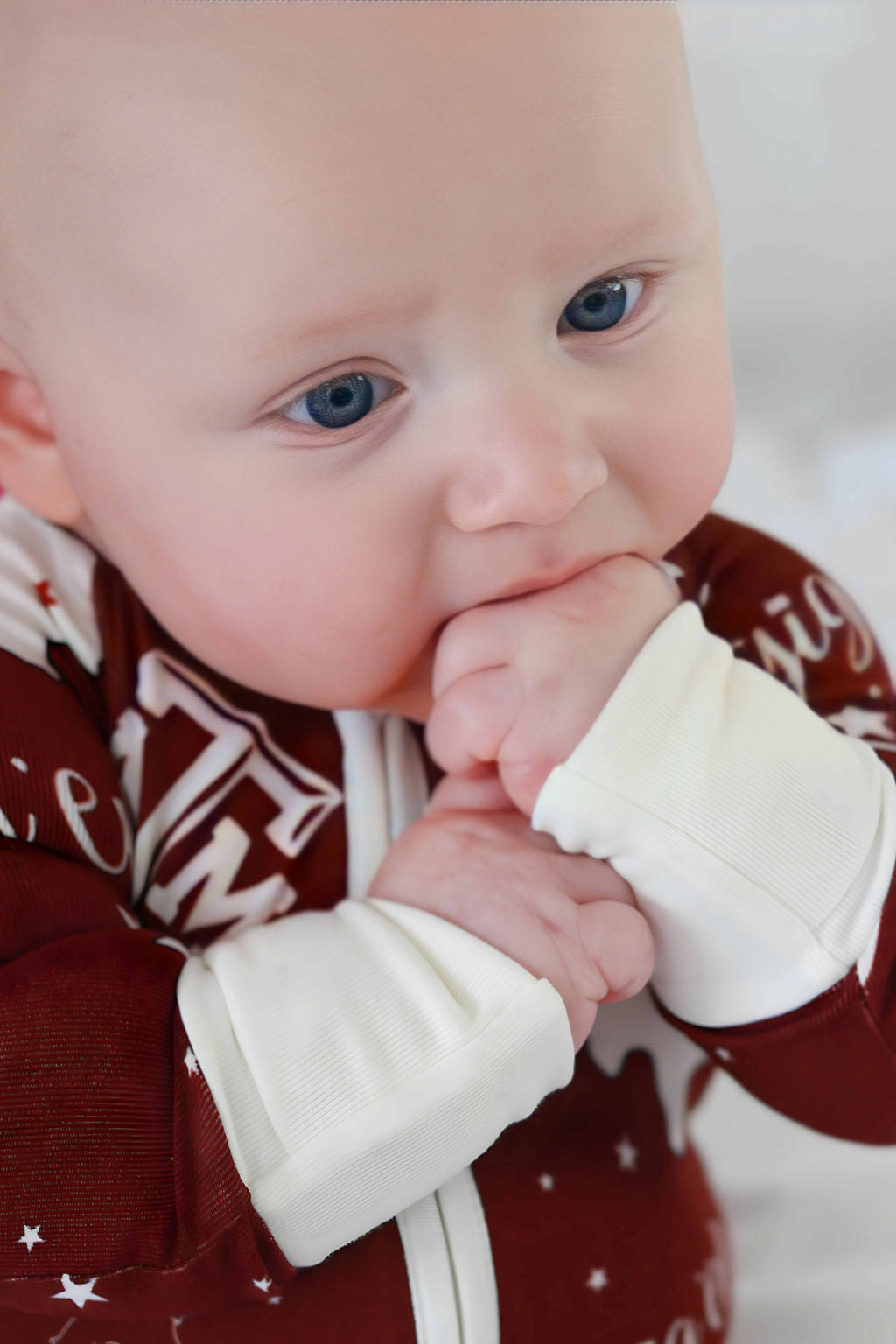 Baby with hands in mouth up close of ribbed bamboo texture