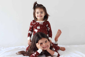 Toddler sitting on toddler sister wearing Texas A&M print