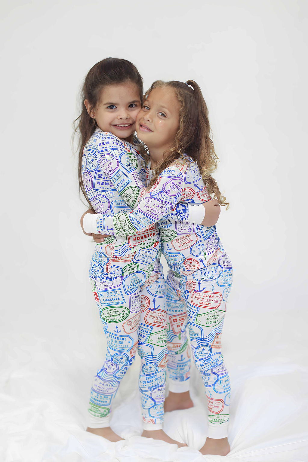 Hugging toddlers in two piece passport stamp travel bamboo pajamas