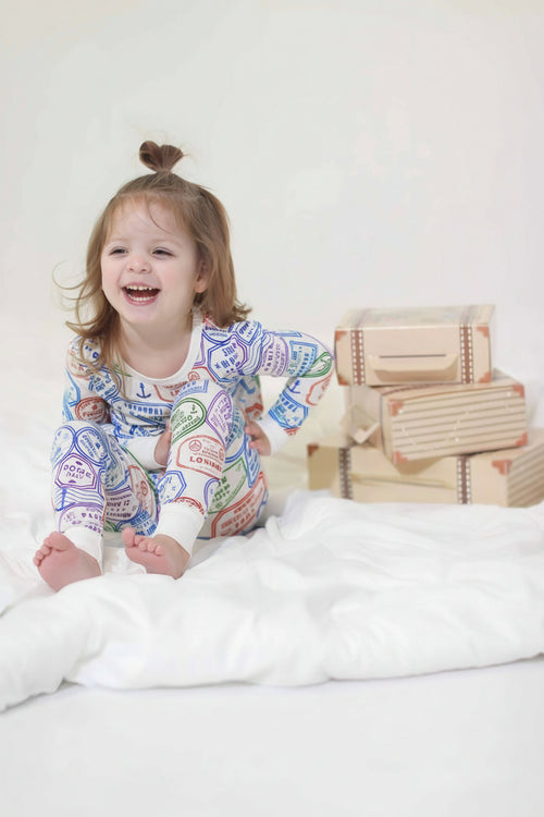 Laughing toddler in passport stamp pajamas